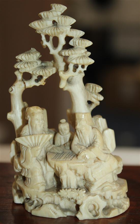 A Chinese ivory group of scholars playing weiqi beneath a pine tree, 19th century, 8.7cm, wood stand, slight repair